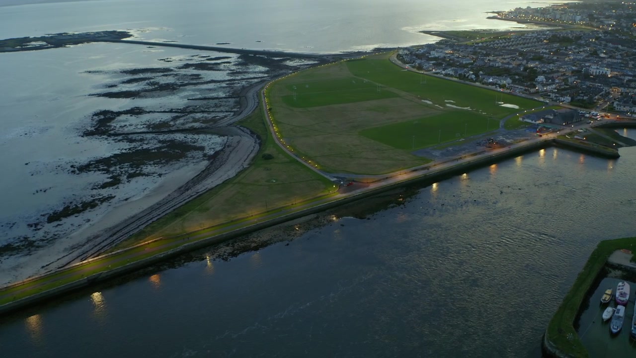 Omvendt luftfoto avslører Nimmo's Pier i skumringen med lysene på, Claddagh og Galway-kysten
