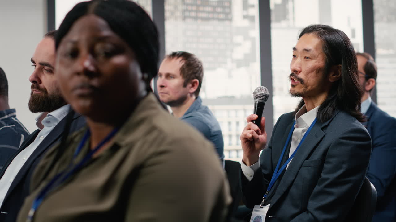 Asian man attendee interacting with public speaker at panel