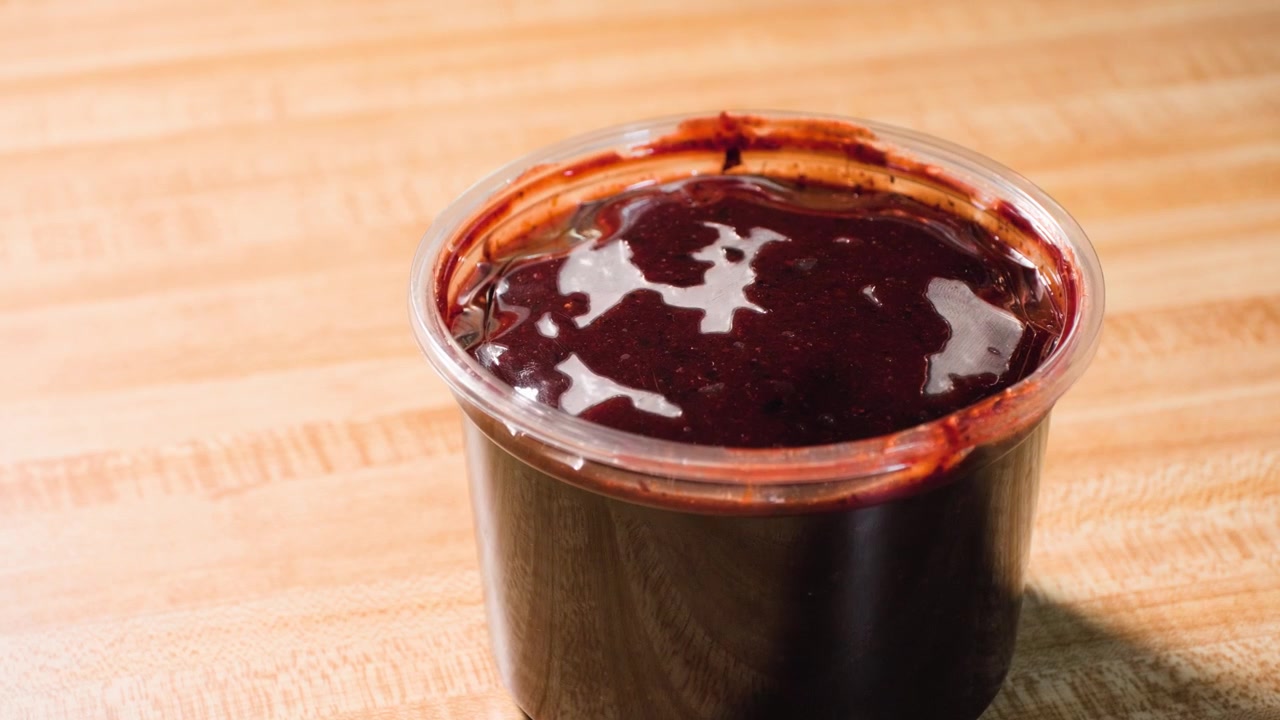 Nærbilde av matlagingsopptak som viser at et plastlokk legges på en beholder for chamoy-saus under tilberedning av en hjemmelaget chamoy-sausoppskrift fra bunnen av