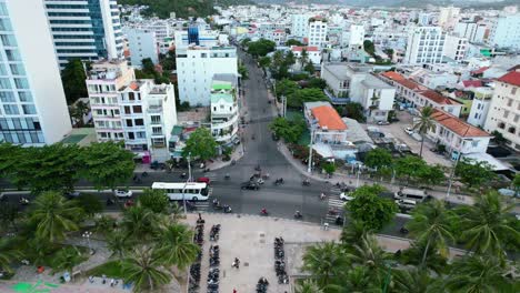 static-aerial-top-down-view-of-an-intersection-along-the-coastal-road-in-Nha-Trang-Vietam-located-in-Khanh-Hoa-province-during-a-cloudy-sunset-as-motorbikes,-cars,-and-busses-drive-along-the-road