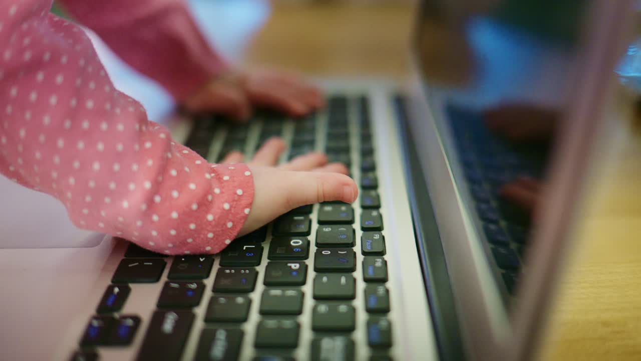 Close-up of Baby's Hands Exploring a Laptop Keyboard