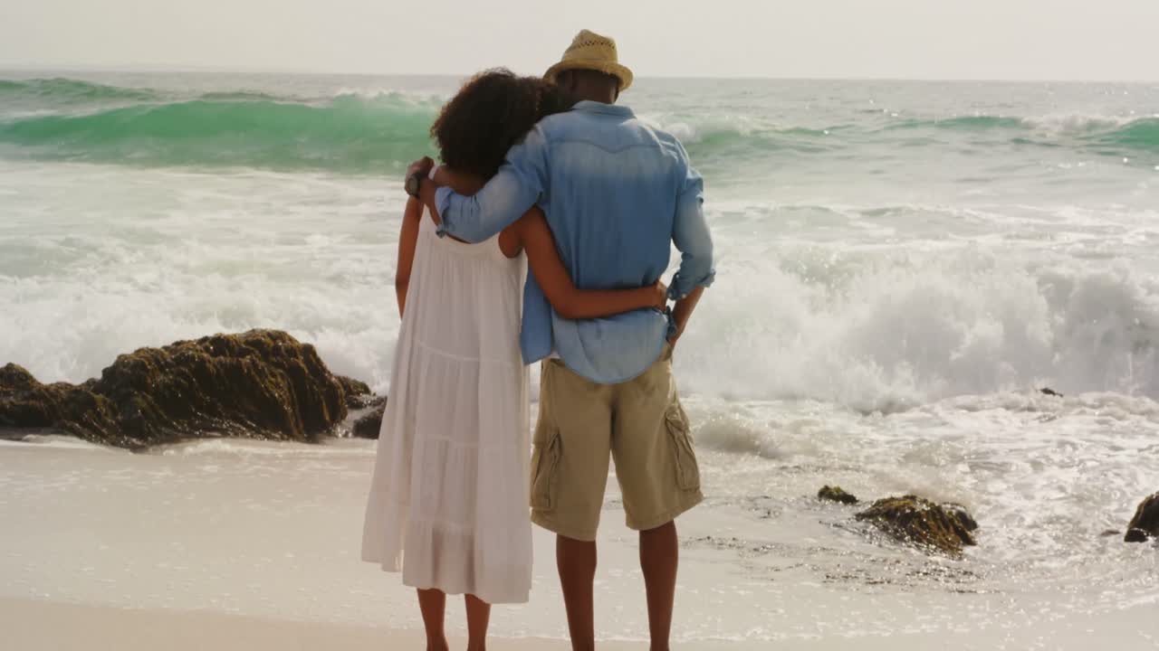 Rear view of African american couple standing together on the beach 4k
