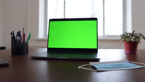 green screen laptop computer sitting on a home work desk.