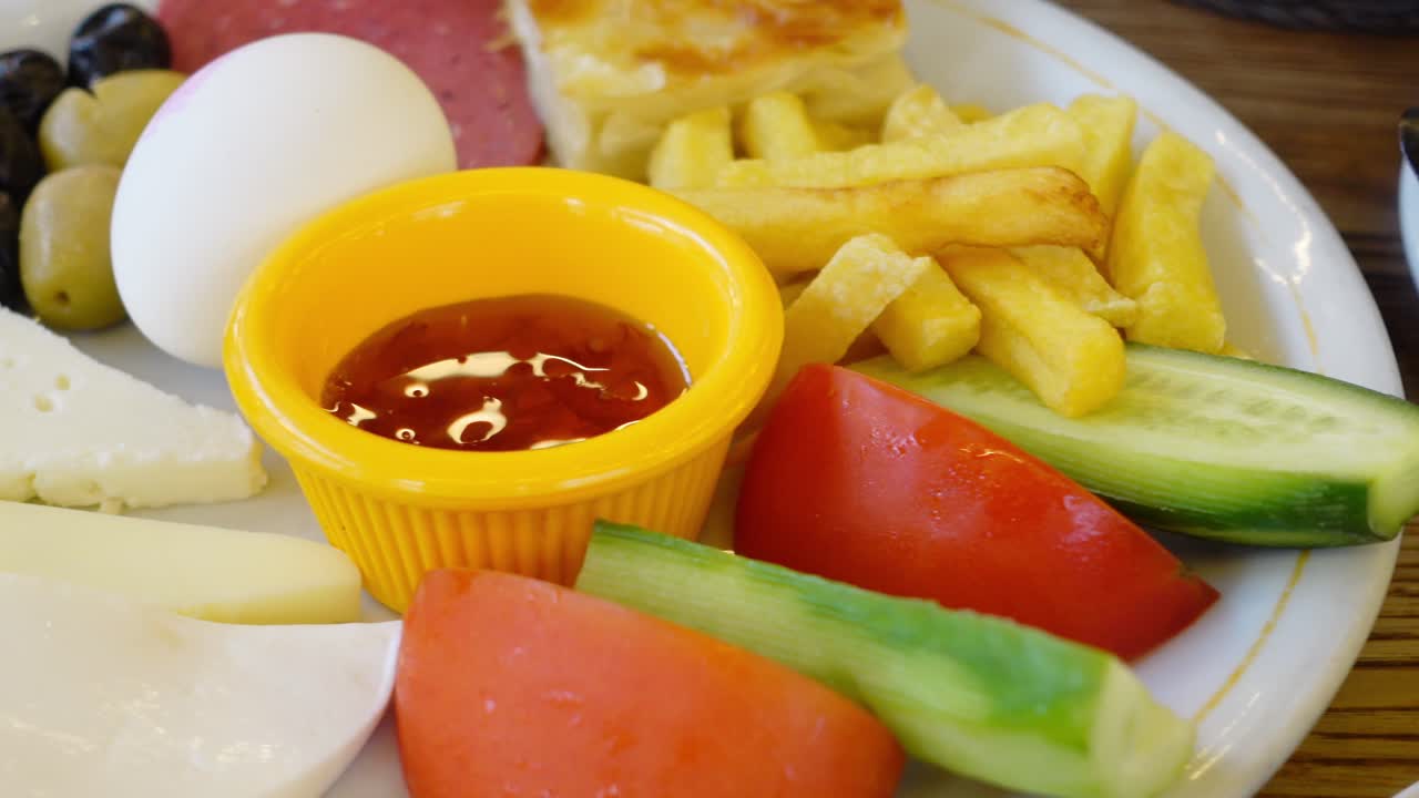 desayuno turco con huevos, queso, aceitunas, tomates, pepinos, papas fritas, pan y salchichas