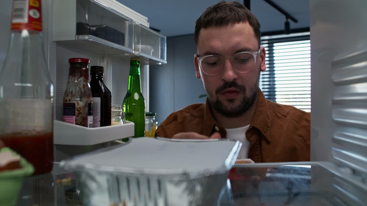 Man eating a snack from the refrigerator at night