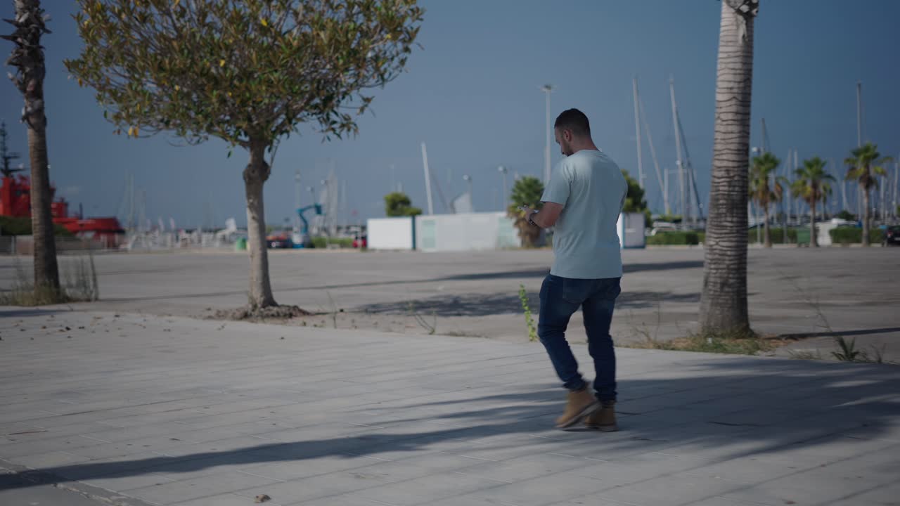 Man walking outdoors, using a smartphone