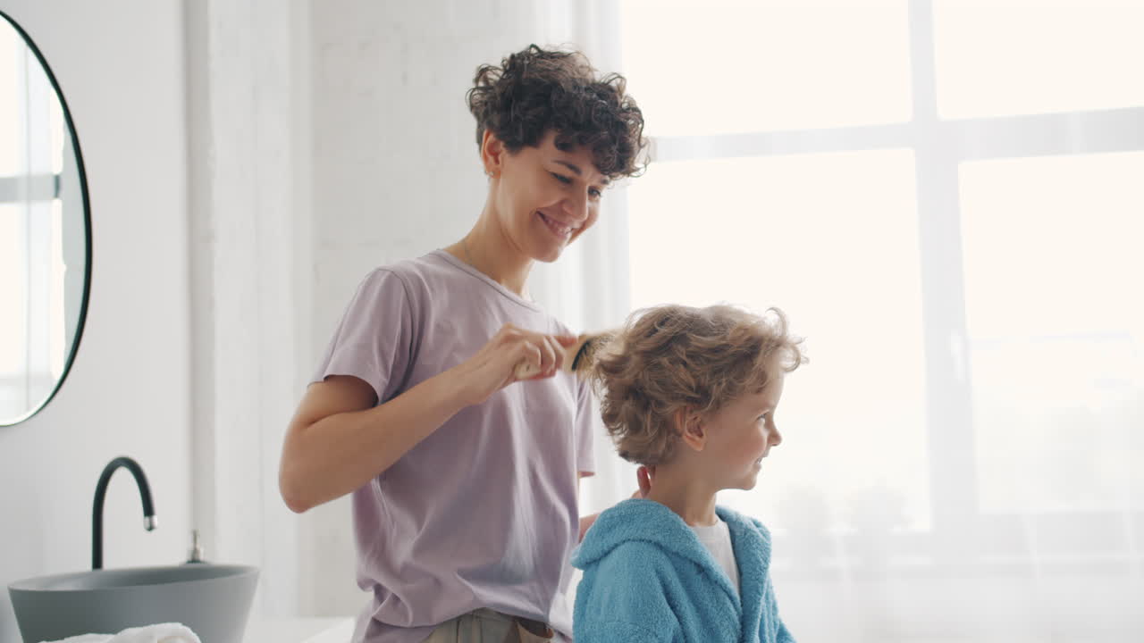 Mother brushing daughter's hair in the bathroom