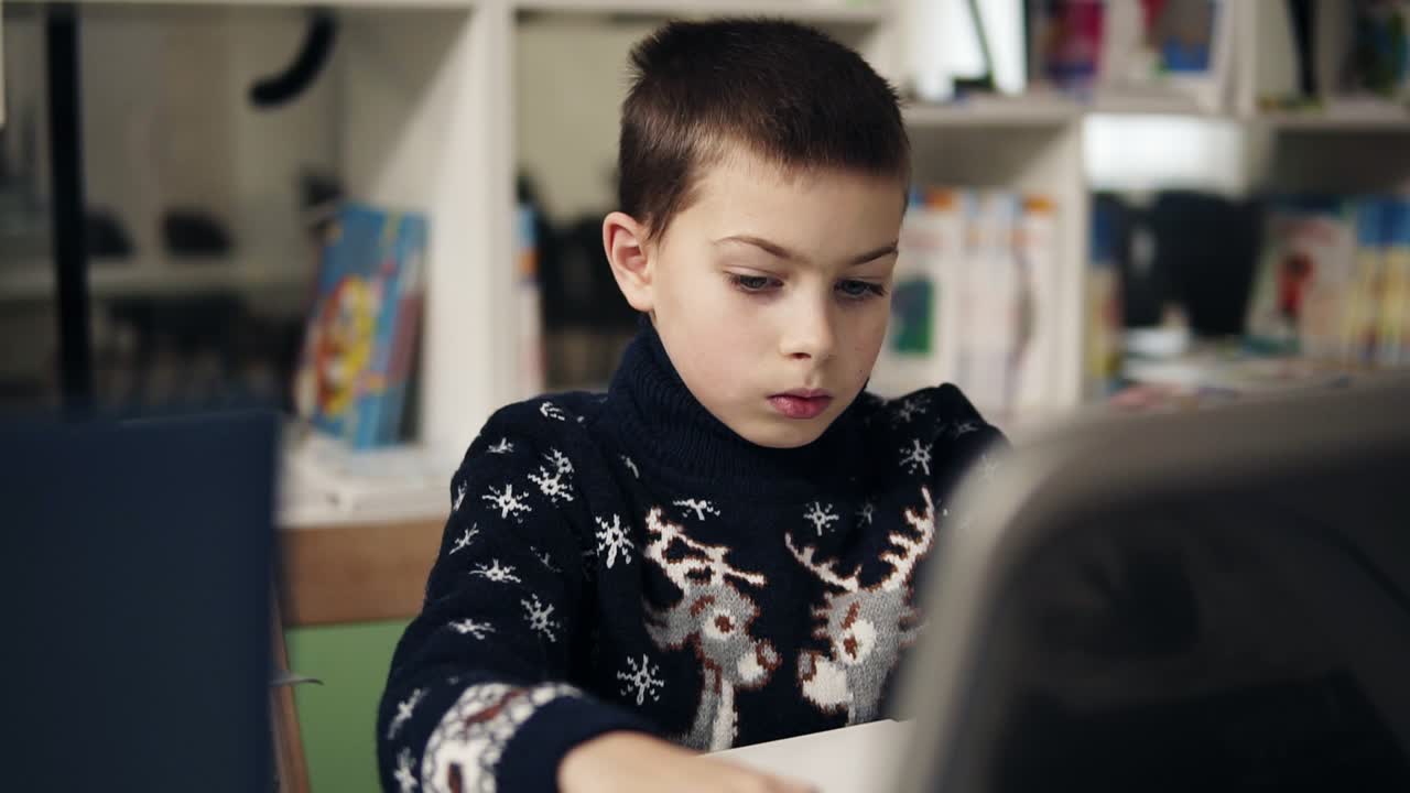 imágenes en cámara lenta de un niño pequeño con grandes ojos azules retrato, sentado frente a la pantalla del portátil. clase de programación. proceso educativo.
