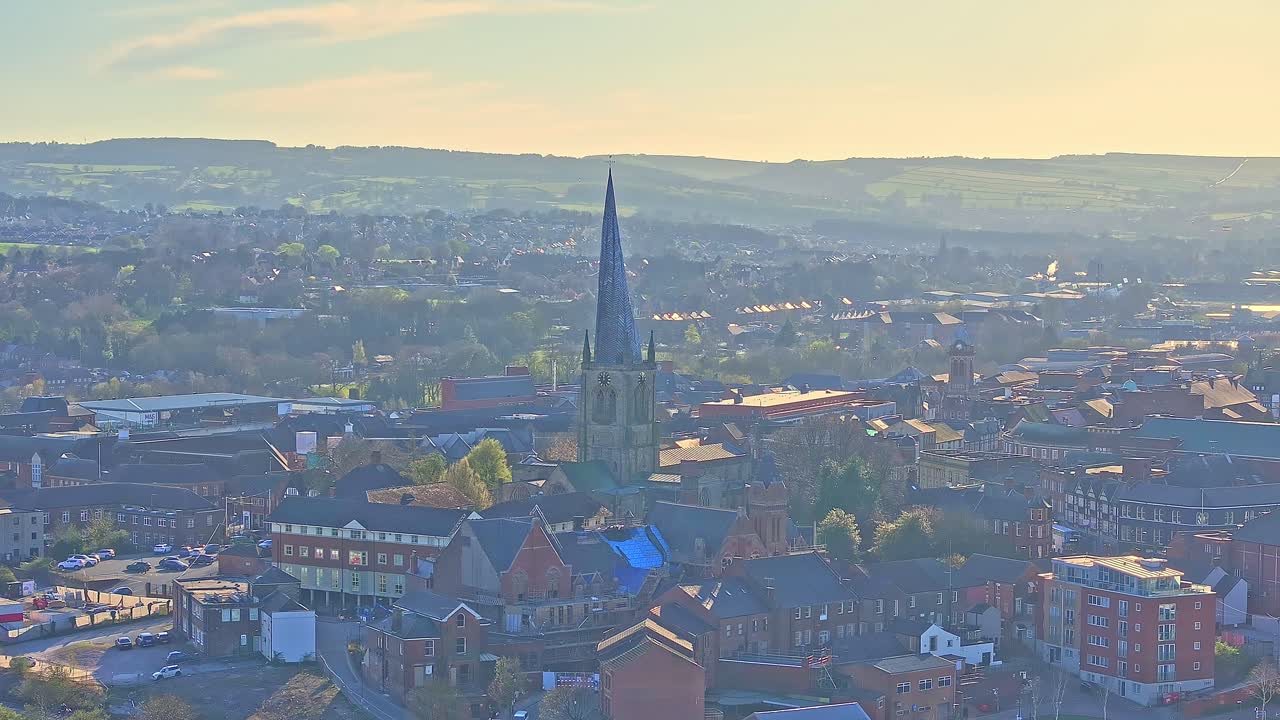 Aerial view of Cathedral church (Chesterfield Spire) in the town of Chesterfield, Derbyshire district, England. Morning light glow over the hills in the horizon.