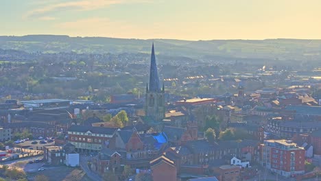 aerial view of cathedral church (chesterfield spire) in the town of chesterfield, derbyshire district, england. morning light glow over the hills in the horizon.