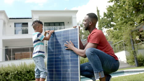 african american man and his son install a solar panel outdoors at home