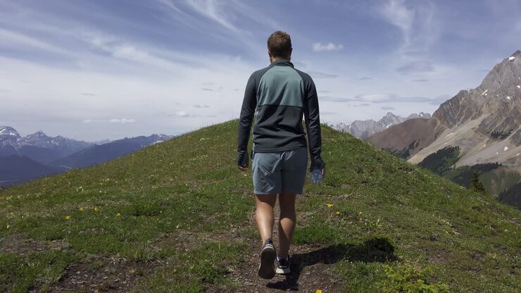 Hiker walking on top of mountain plane revealing peak, Rockies, Kananaskis, Alberta Canada