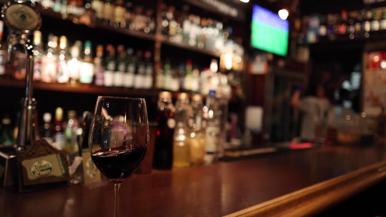 una copa de vino tinto en un mostrador de bar pulido.