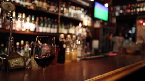 um copo de vinho vermelho num balcão de bar polido.