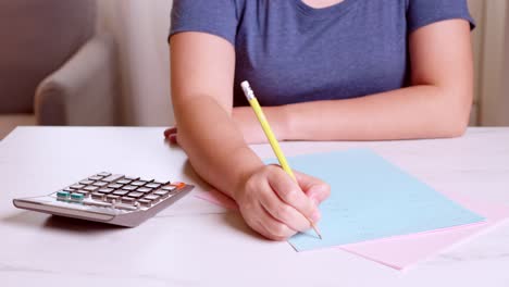 la mujer está usando una calculadora para calcular y anotar sus gastos contables mensuales en casa