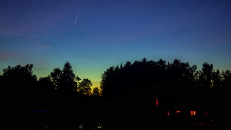 shot of sun coming out over village house surrounded by trees just before sunrise in timelapse