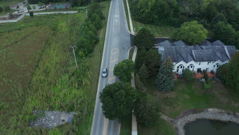elevated aerial drone footage following a street through a scenic lush suburban neighborhood landscape of middle-class america