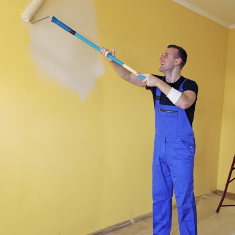man painting wall with paint roller. young handsome man painting wall, redecorating room