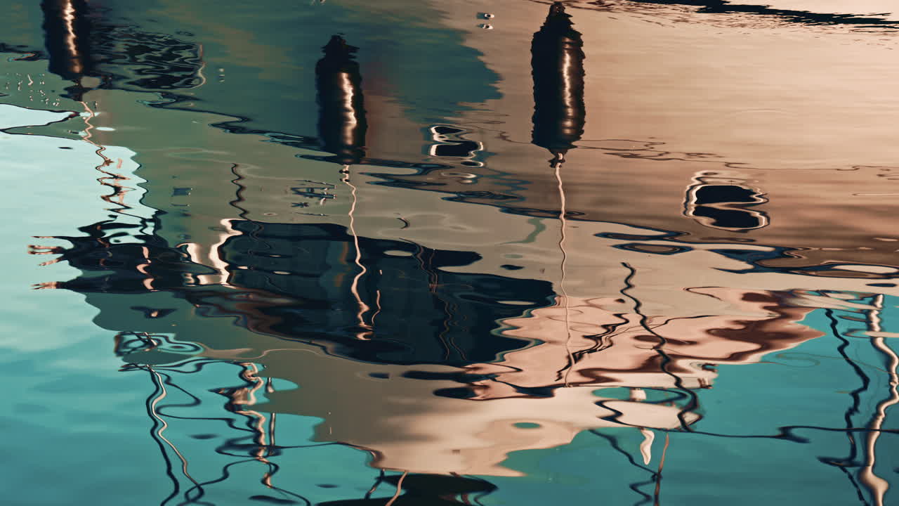 An abstract reflection of boats and harbor structures on slightly wavy water, creating a painterly, distorted look