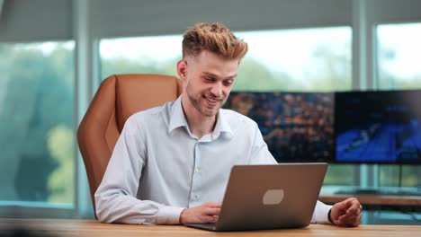 Joven-Empresario-Dedicado-A-Videollamadas-En-Un-Portátil-En-Una-Oficina-Moderna