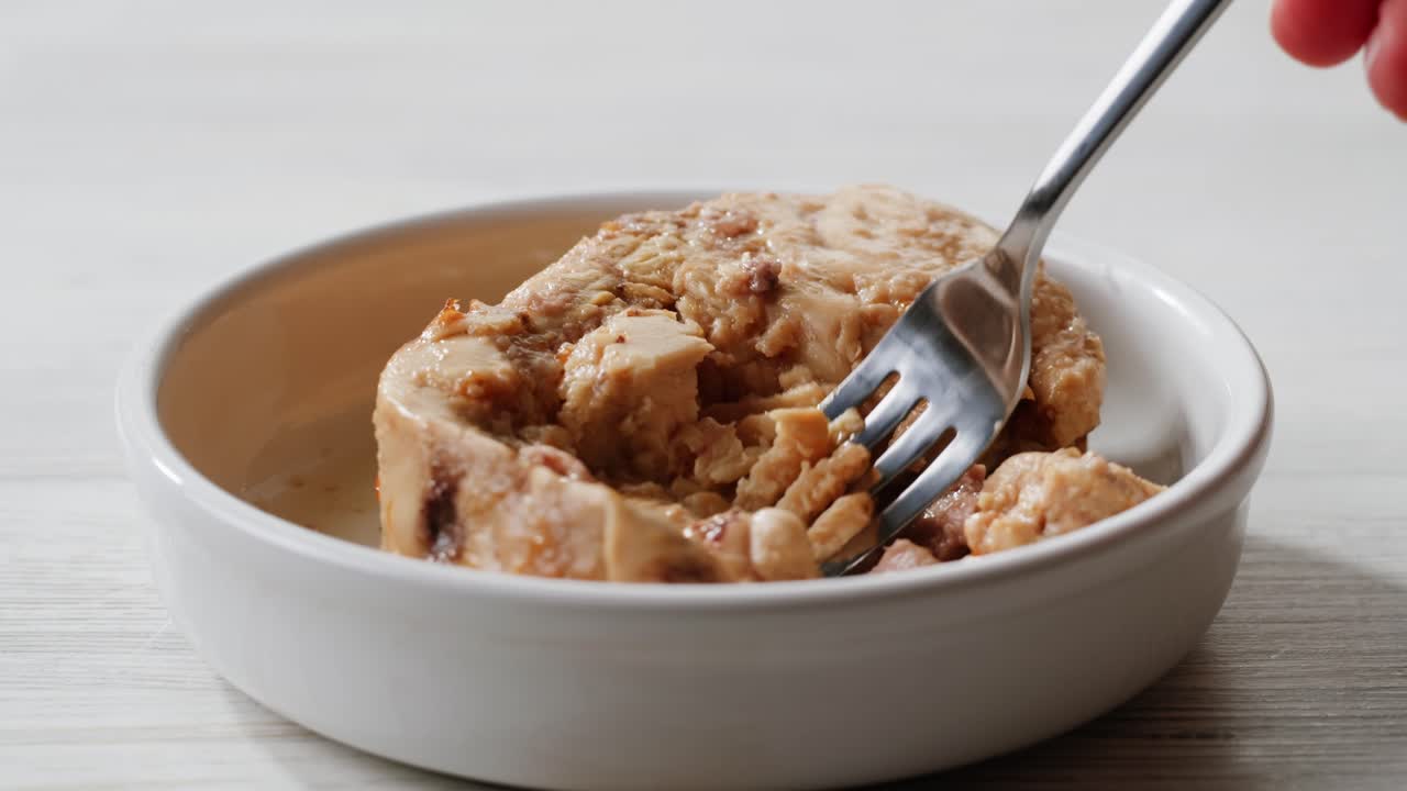 Smoked cod liver in oil in open tin can with fresh greens on wooden table. Seafoods delicacy. High quality 4k footage