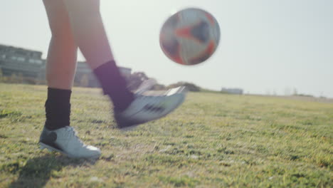 female soccer player practicing kick-ups on green lawn