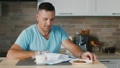 a young man reading a book in the kitchen standing next to a glass of milk a healthy diet and lifest