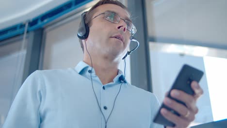 focused male operator in wired headset holding cell phone