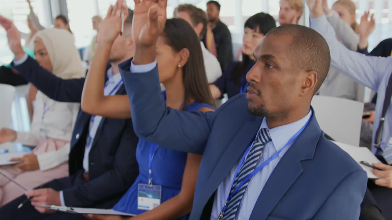 Audience at a seminar raising hands to ask questions