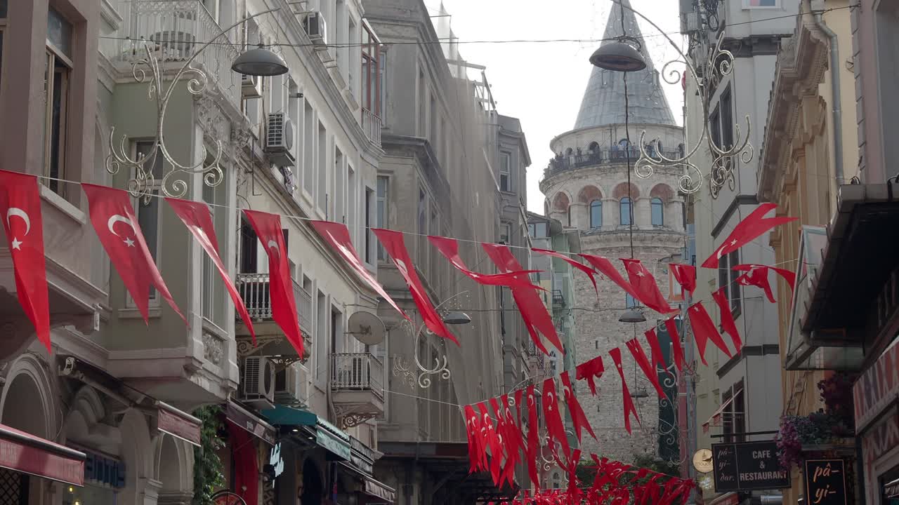 una calle estrecha en estambul, turquía, con la torre galata en el fondo.