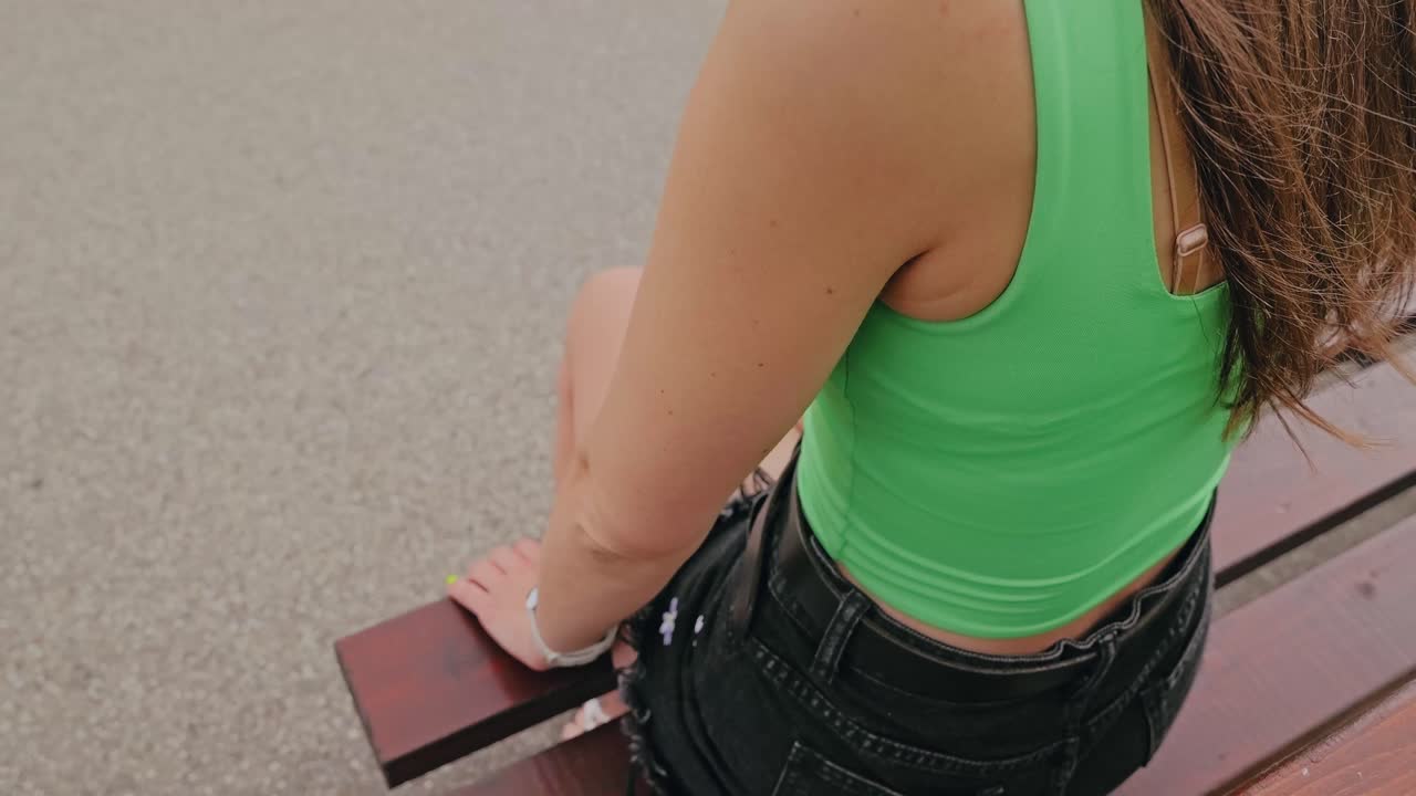 Slow motion of woman in green shirt pressing glucose sensor on skin outdoors