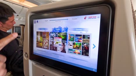 passenger using touch screen monitor on airplane