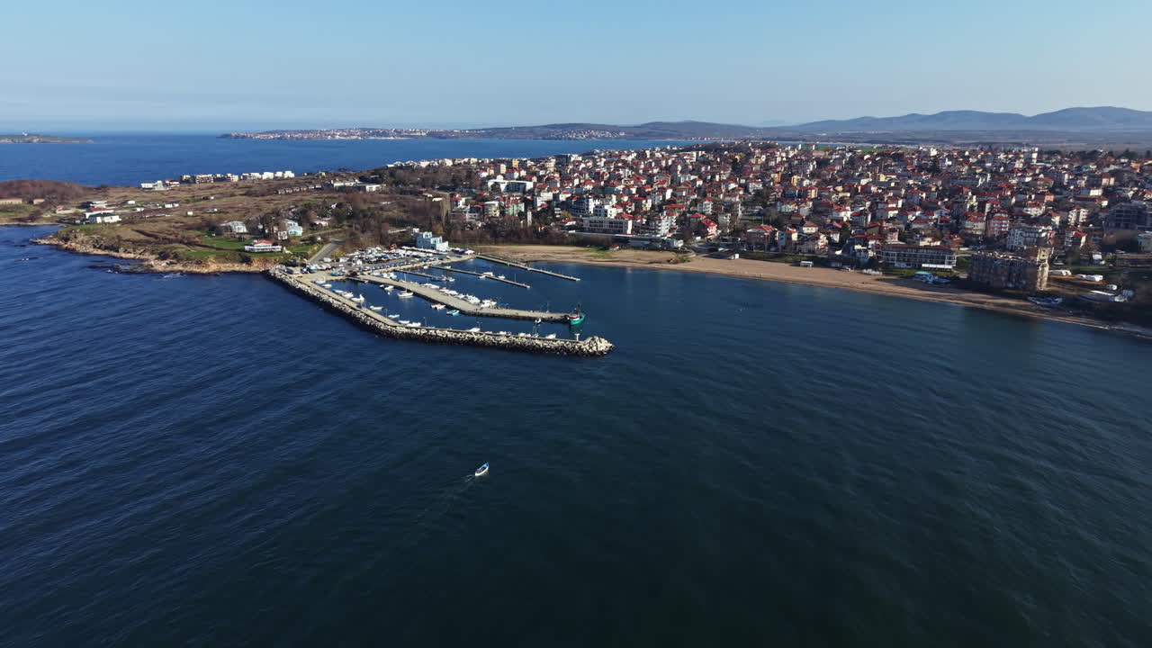 Vista costiera di un porto turistico e una città sul mare durante una giornata serena con barche ormeggiate ed edifici sullo sfondo