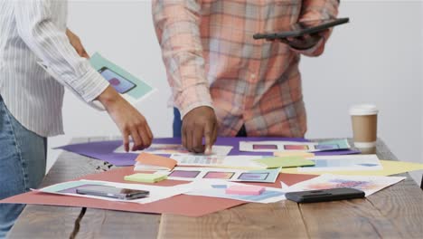 midsection of african american male and female creatives using tablet brainstorming, slow motion