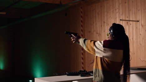 mujer alegre en el campo de tiro probando un nuevo modelo de arma