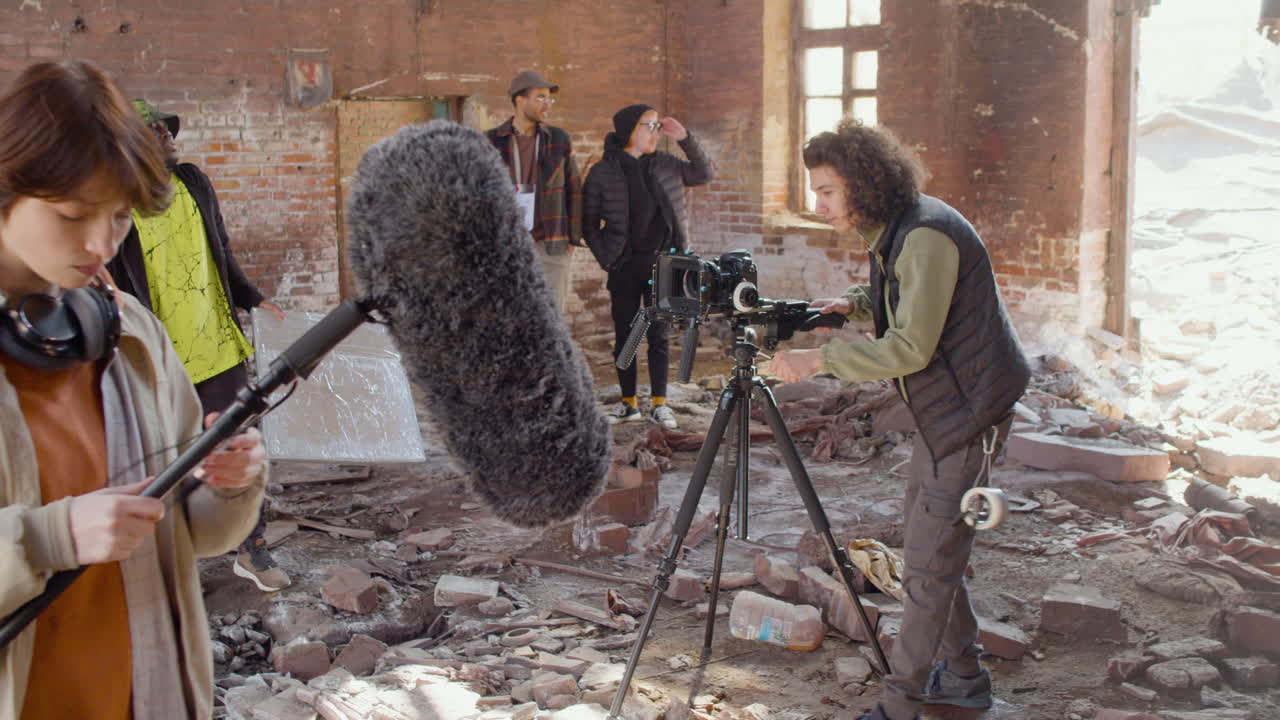 dos compañeros de producción preparándose para grabar en un edificio en ruinas