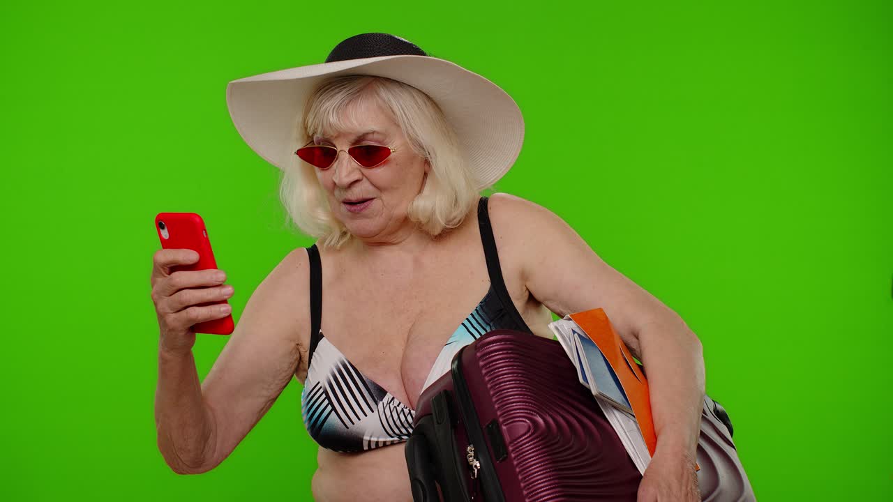 Anziana turista pensionata che si scatta un selfie, facendo una videochiamata con il cellulare.