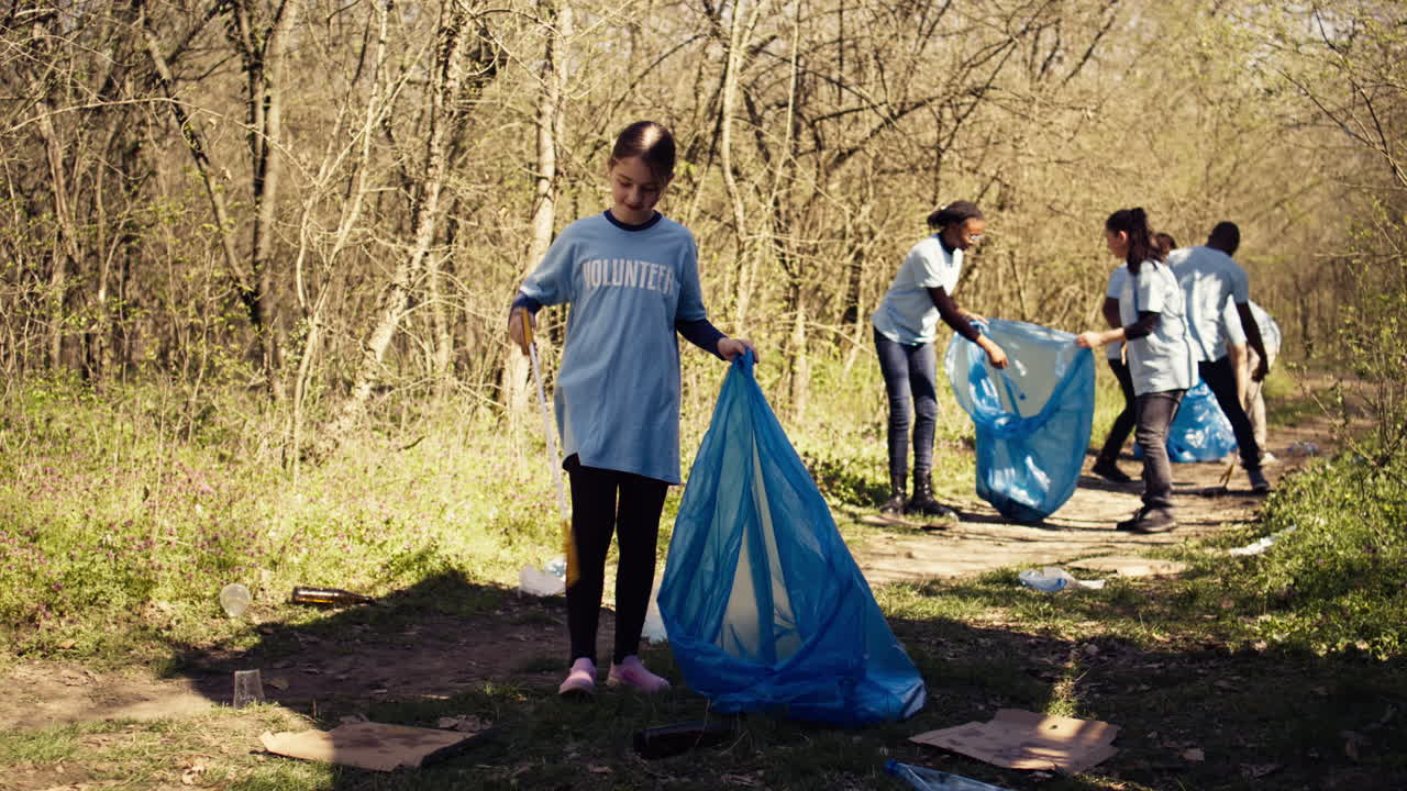 niña recolectando basura alrededor de un bosque con una herramienta de garra y bolsas de basura