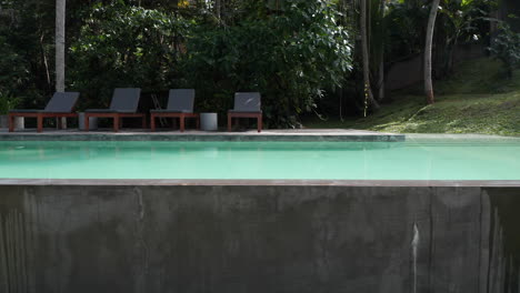 lounge chairs at the poolside of a private resort in tropical countryside of sri lanka