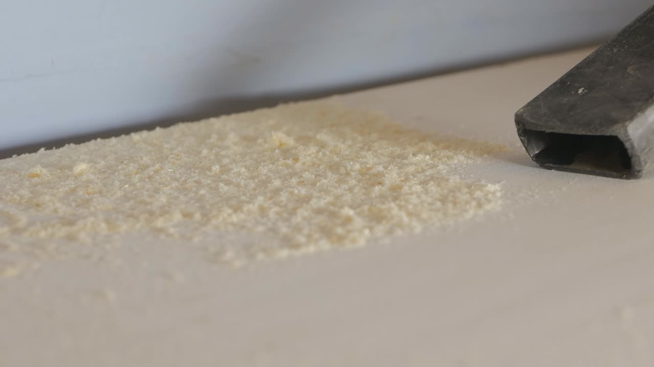 진공청소기는 목공의 테이블에서 나무 꺼기와 도자기를 흡수합니다. 작업 일 끝에 작업 장소의 청소. 근접.