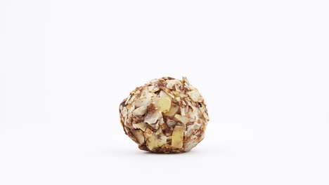 one truffle dark chocolate dessert with chopped almonds. rotating on the turntable. isolated on the white background. close-up. macro.