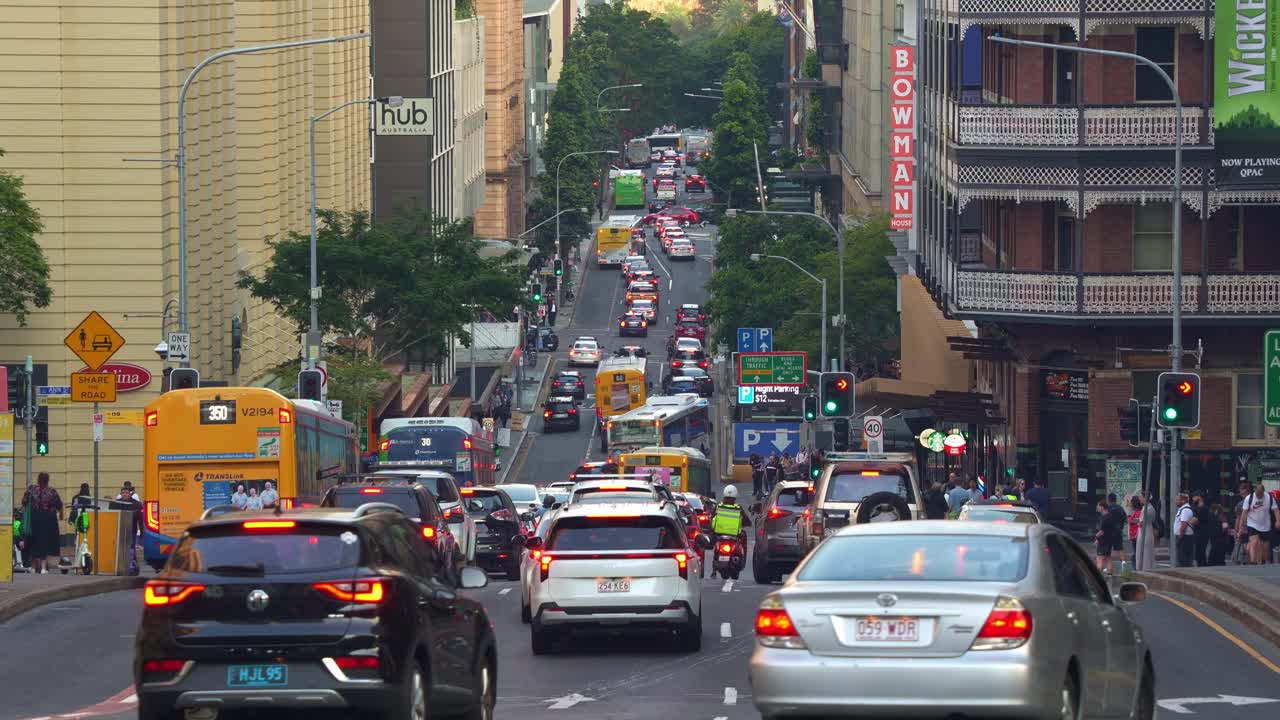 Bottleneck traffic on Edward Street in Brisbane central business district during peak hours, with pedestrians crossing, buses and cars driving and running in all directions.