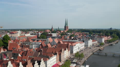 Vuelo-Hacia-Adelante-Hacia-Luebeck-Dom,-Gran-Catedral-De-Ladrillo.-Vista-Aérea-Del-Centro-Histórico-De-La-Ciudad.-Edificios-Altos-A-Orillas-Del-Río-Con-Frontones-Decorativos.-Lübeck,-Schleswig-Holstein,-Alemania