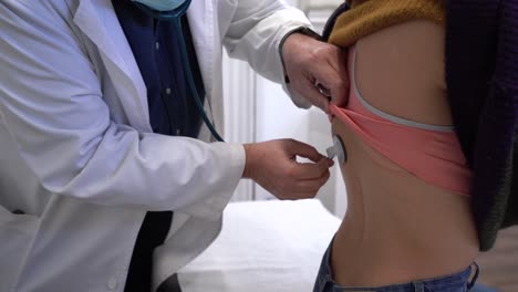 médico de cabecera que utiliza el estetoscopio y examina los pulmones del paciente