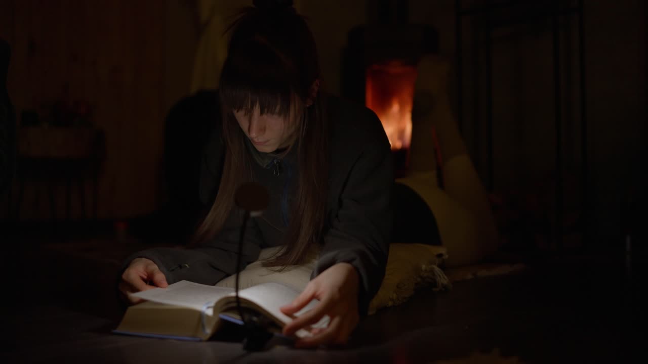 mujer leyendo un libro junto a la chimenea