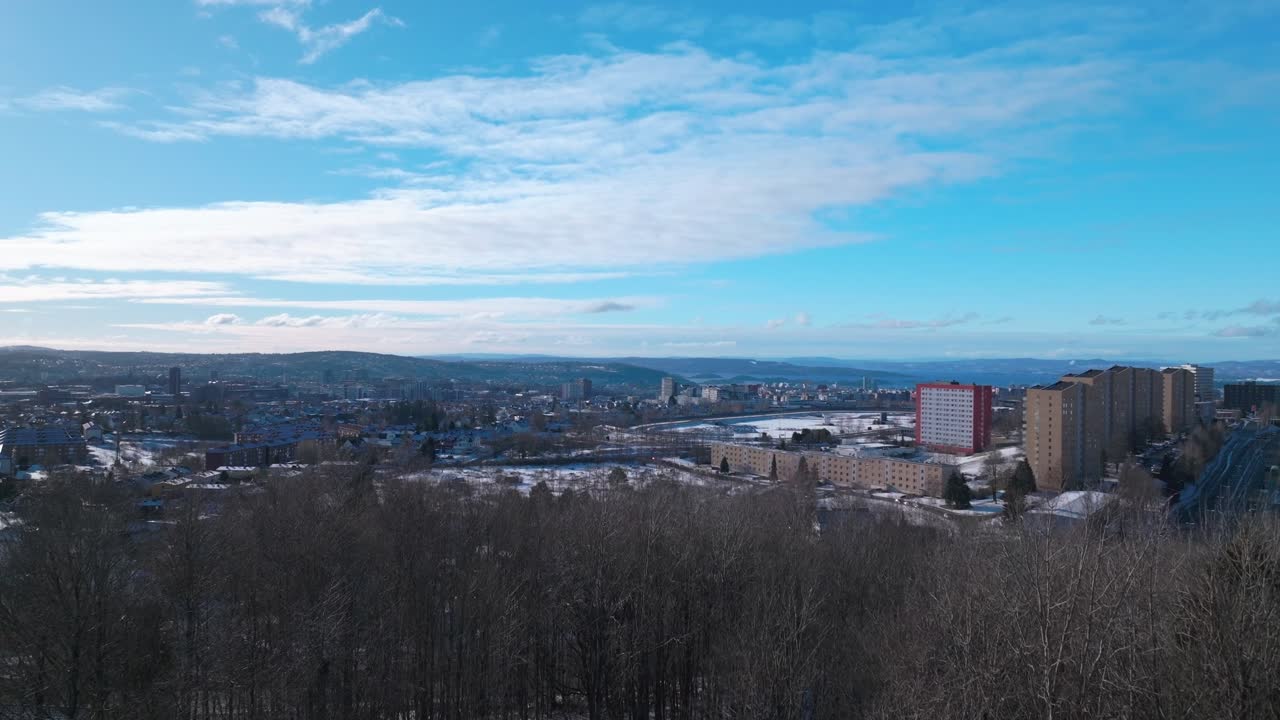 Sunny blue sky daytime Oslo Norway Norge aerial drone Norwegian arctic winter Bjerke Travbane Tonsenhagen apartment buildings Nordmarka forest icy snowy trails highway cars upwards motion