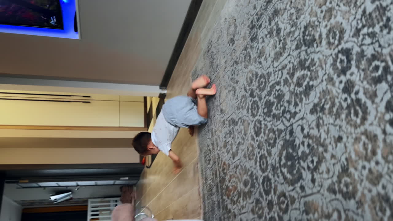 Active Caucasian toddler playing in the room at home. Lovely boy takes the toy and comes up to camera. Vertical view.