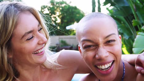 Portrait-Of-Two-Female-Friends-Outdoors-Relaxing-In-Swimming-Pool-And-Enjoying-Summer-Pool-Party