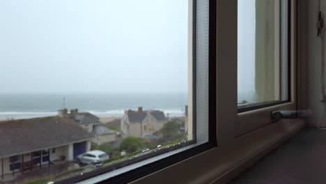 rain flowing down a window with the ocean visible in the background in slow motion