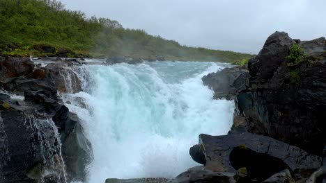 river with a mighty waterfall near the forest and between the black rocks